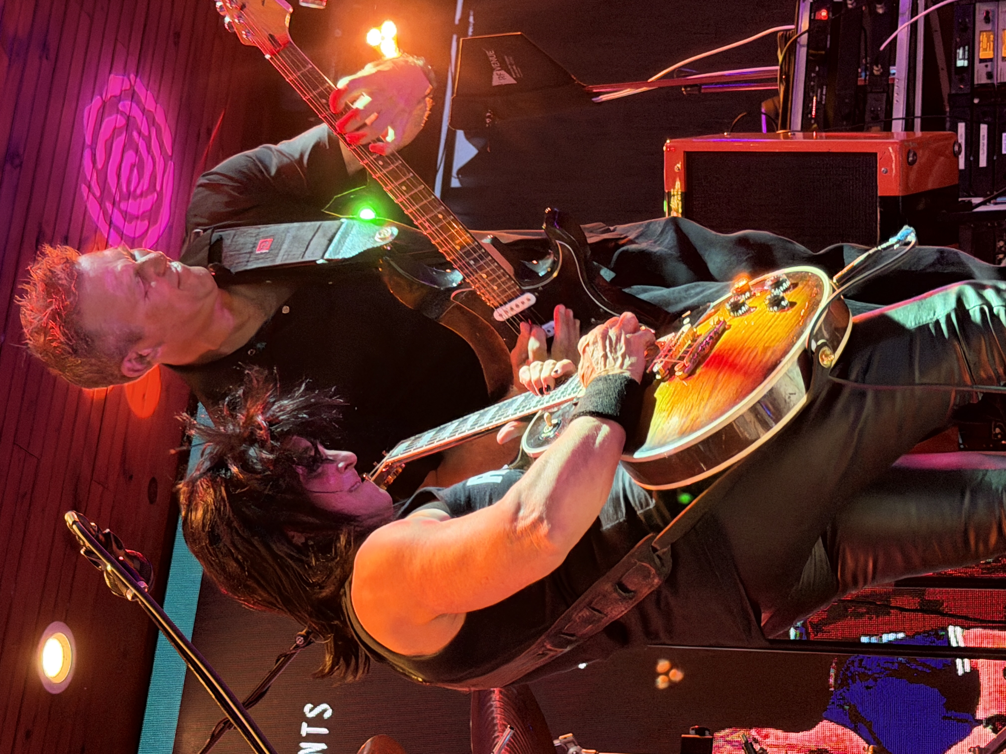 Guitarists trading riffs under the stage lights